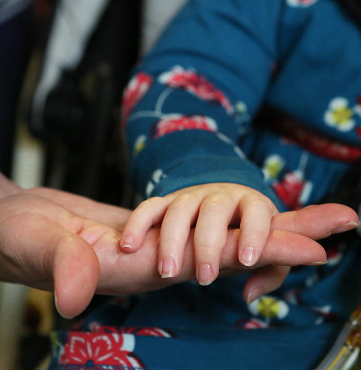 Canuck Place child holding hands with Canuck Place staff member